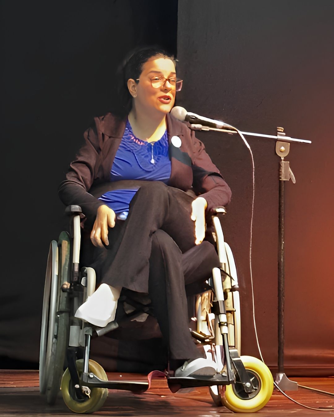 Camilla Carvalho falando ao microfone em um evento sobre inclusão e acessibilidade