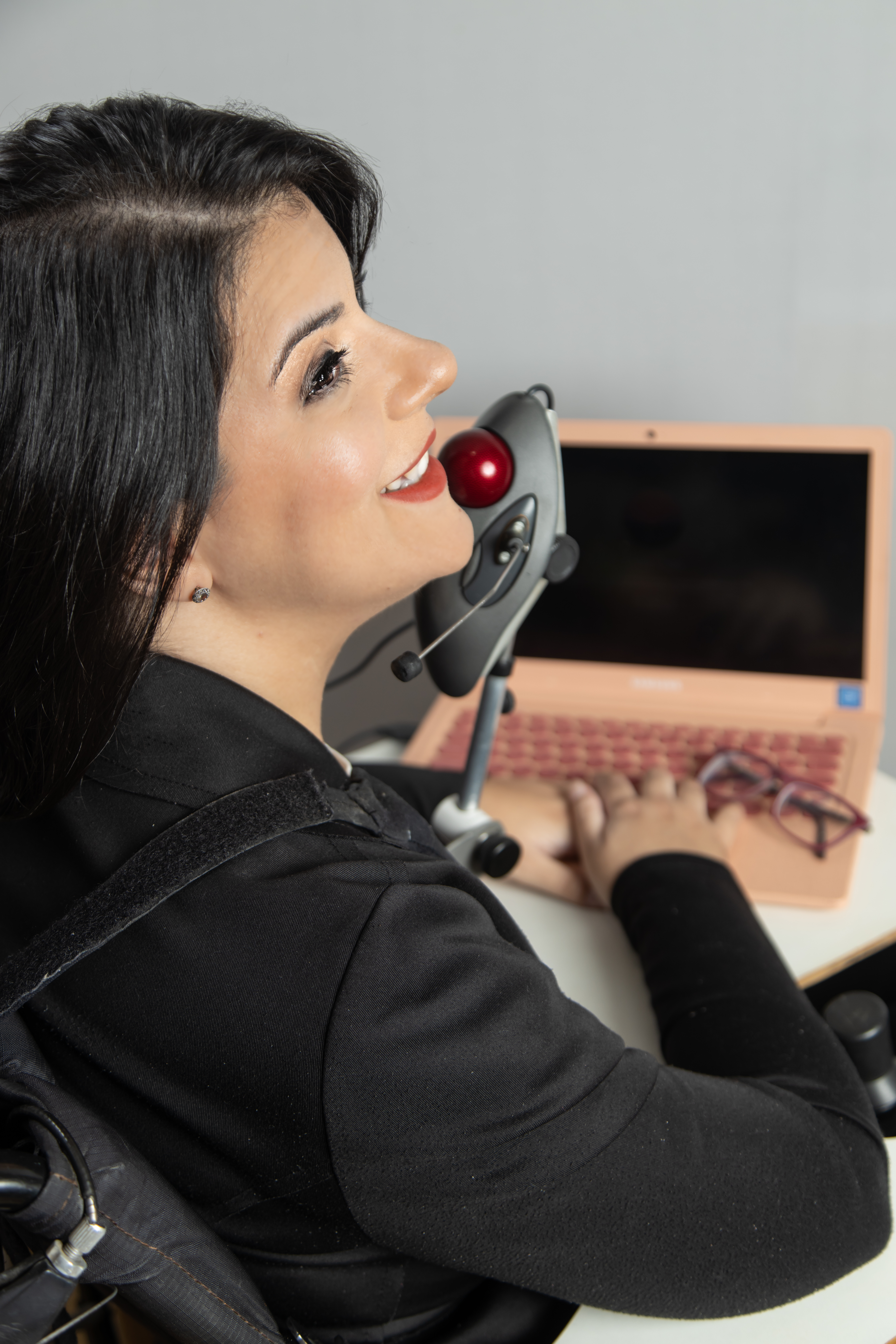 Camilla Carvalho em sua cadeira de rodas, usando computador com recurso de acessibilidade